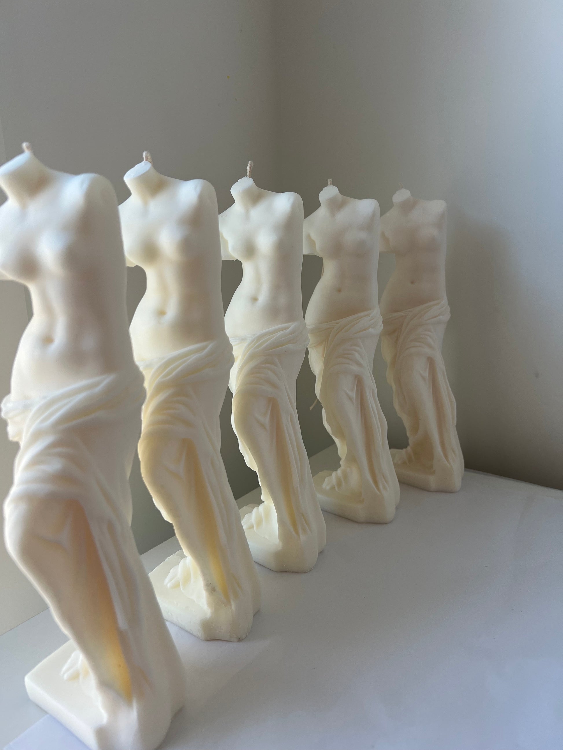 Row of white female torso sculptures on a plain background